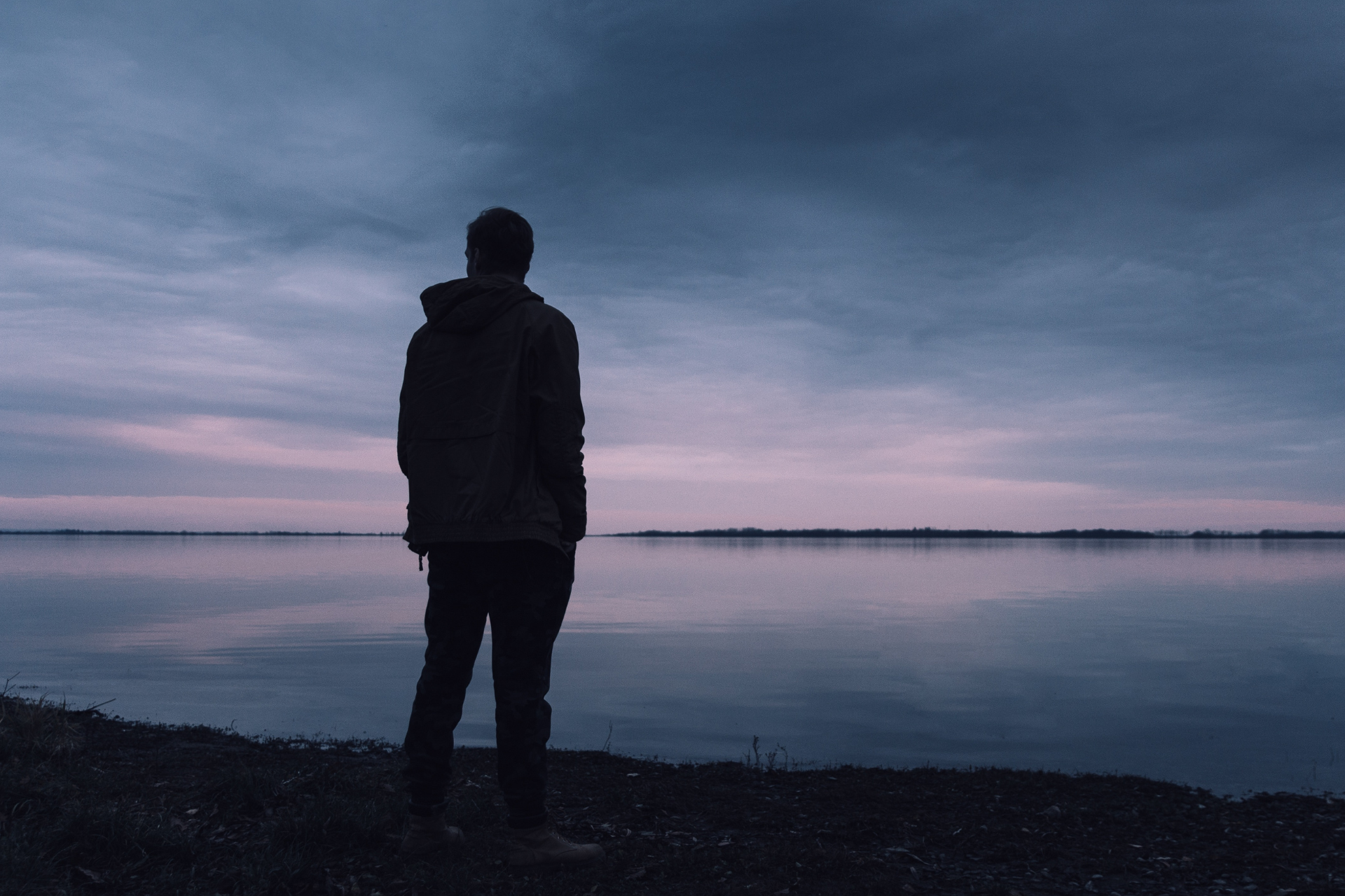 A man standing alone on a beach at sunset, symbolising reflection and healing through borderline personality disorder therapy.