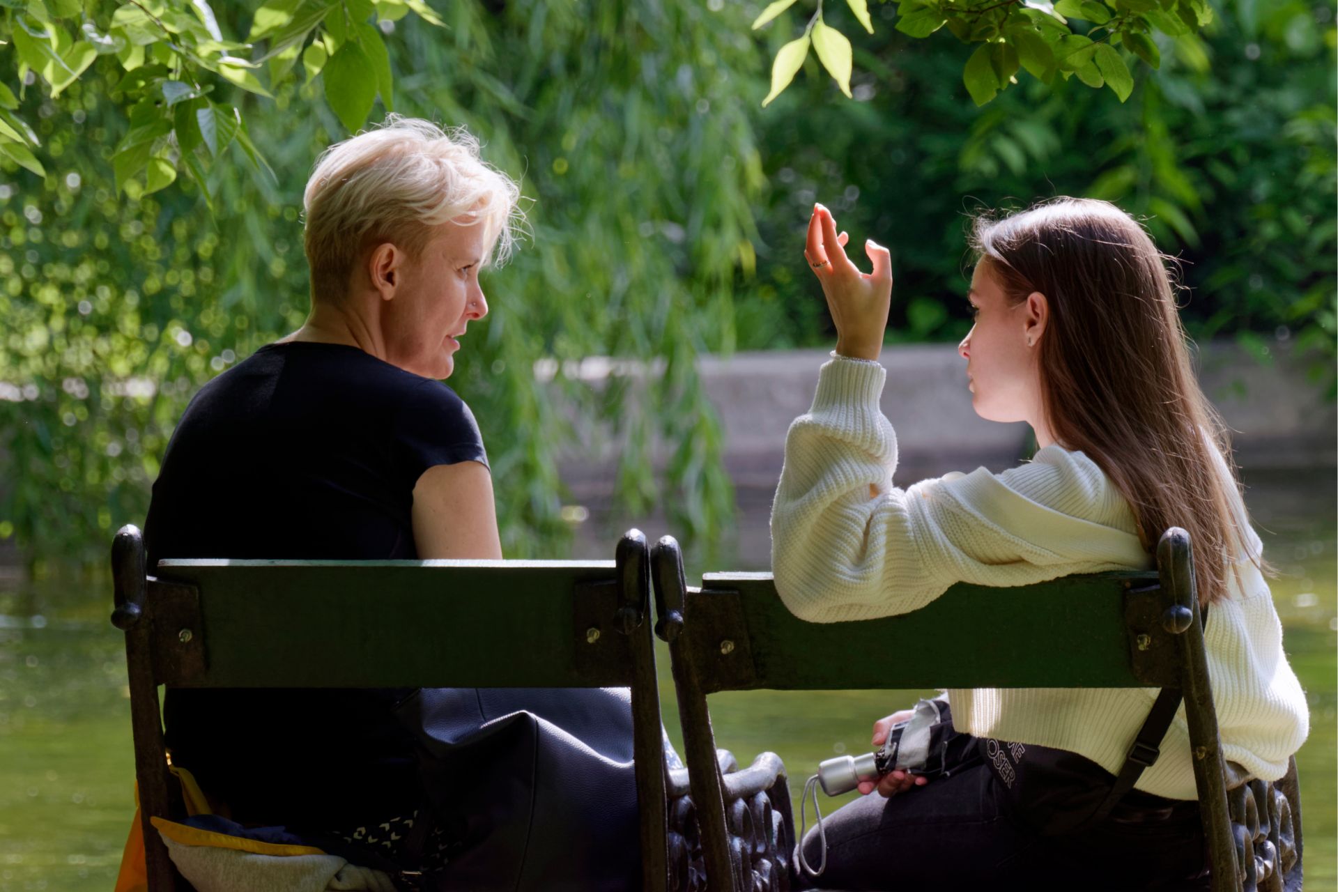 Mother and daughter sitting on a park bench, having a heartfelt conversation about mental health.